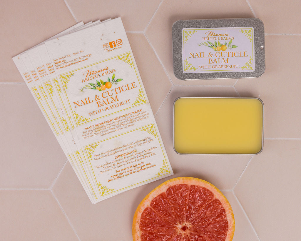 Nail and cuticle balm with grapefruit and display of seeded paper labels on a tiled surface