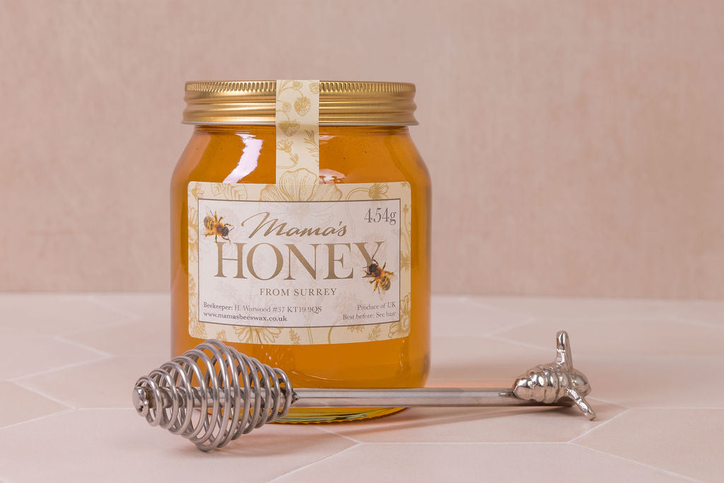 Jar of honey with a honey dipper on a light background