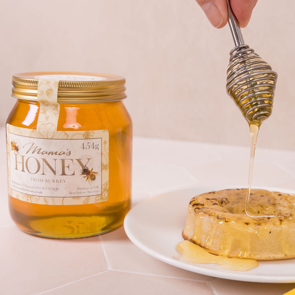 Jar of 'Mama's Honey' with a honey dipper drizzling honey onto a crumpet.