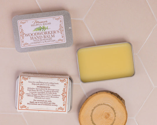 Mama's Woodworker's Hand Balm in a tin with a wooden block on a tiled surface