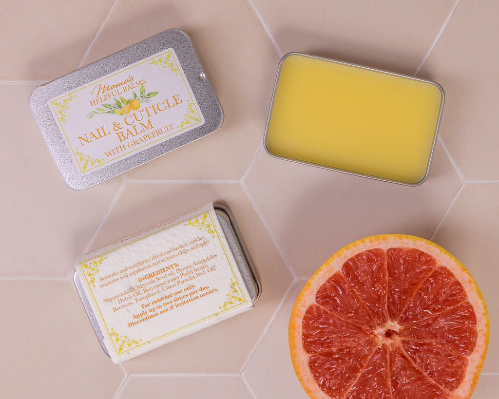 Grapefruit Nail and cuticle balm in a tin with a grapefruit on a tiled surface