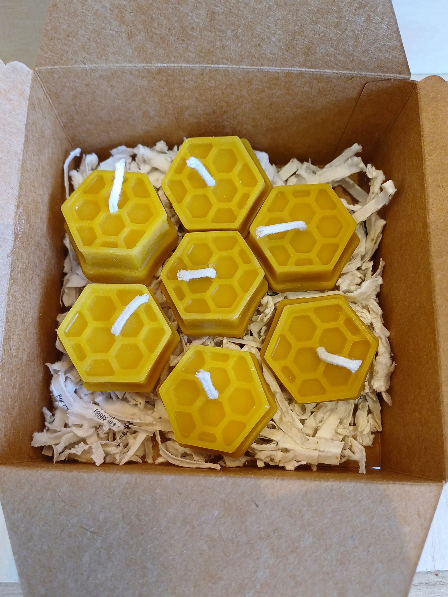 Gift box of 7 pure beeswax tealight candles with a warm golden glow