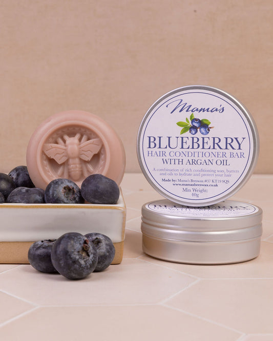 Blueberry hair conditioner bar with aluminium tin on a soap dish and with blueberries