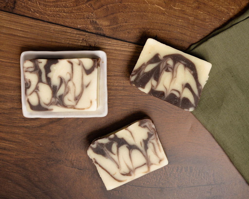 Marbled chocolate orange soap bars on a wooden surface with a green cloth.